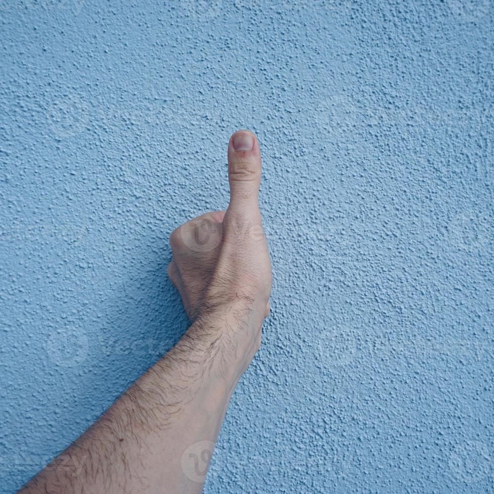 mão gesticulando na parede azul foto