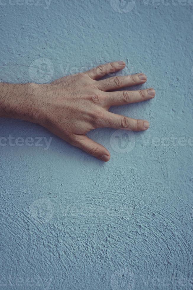 mão gesticulando na parede azul foto