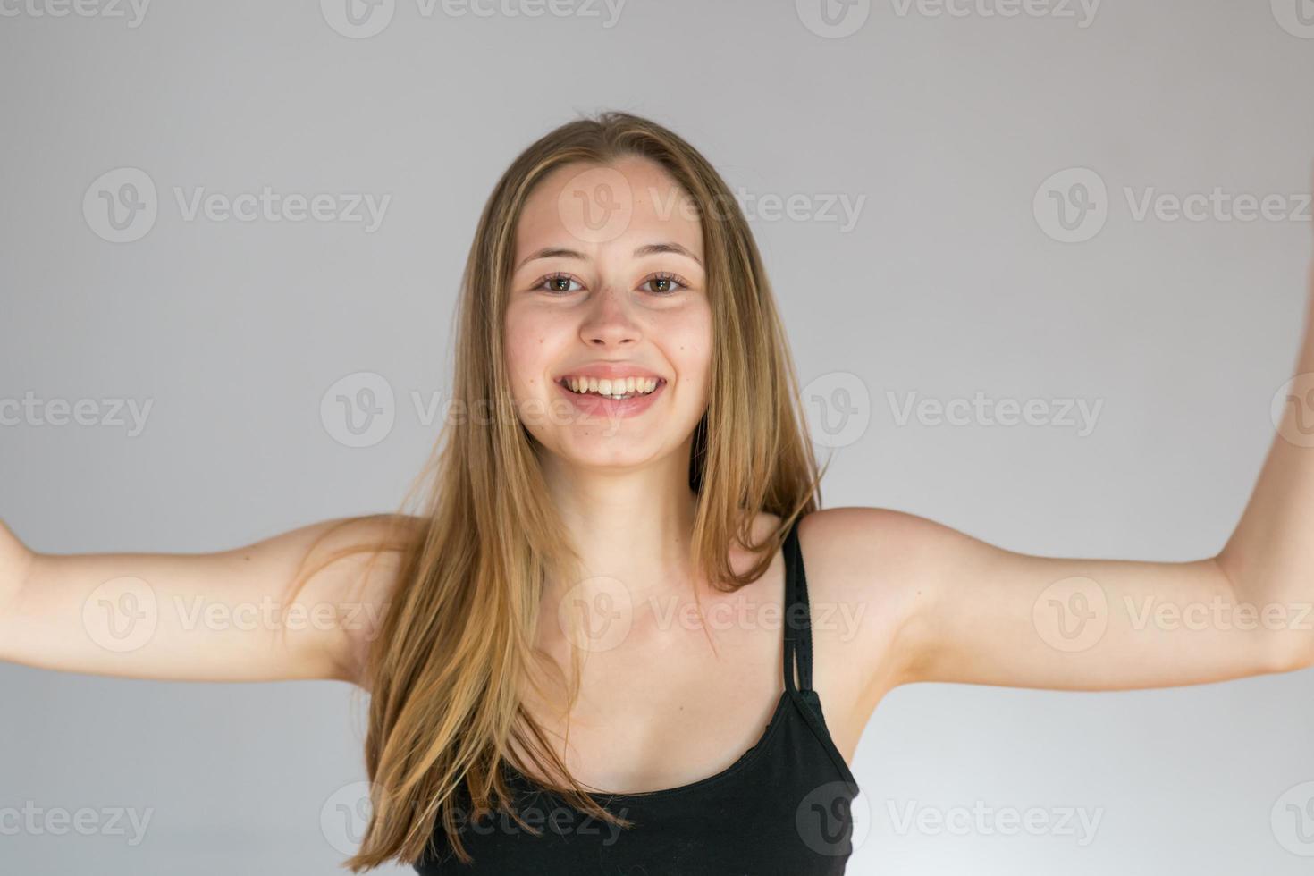retrato de estúdio de uma jovem sorridente posando sobre um fundo cinza, mostrando suas axilas depiladas foto