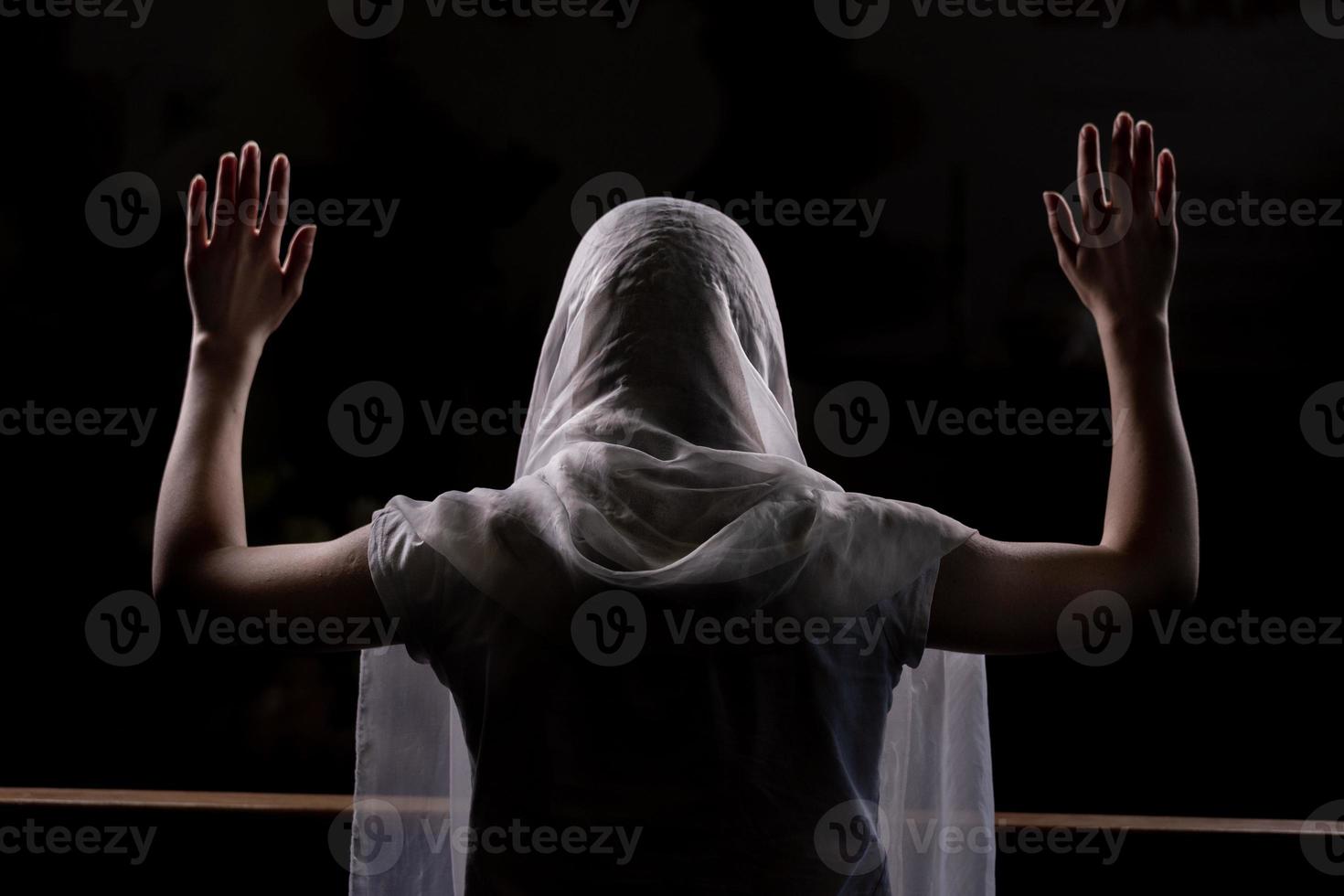 silhueta de uma jovem que está sentada na igreja e orando com as mãos levantadas foto