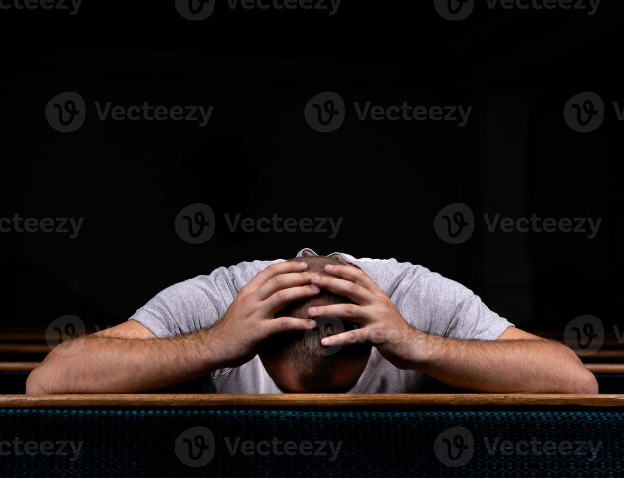 um homem cristão triste de camisa branca está sentado e orando com o coração humilde na igreja foto