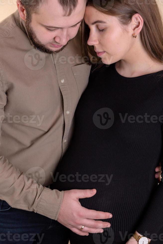 um jovem casal esperando um bebê uma menina grávida em um vestido preto foto