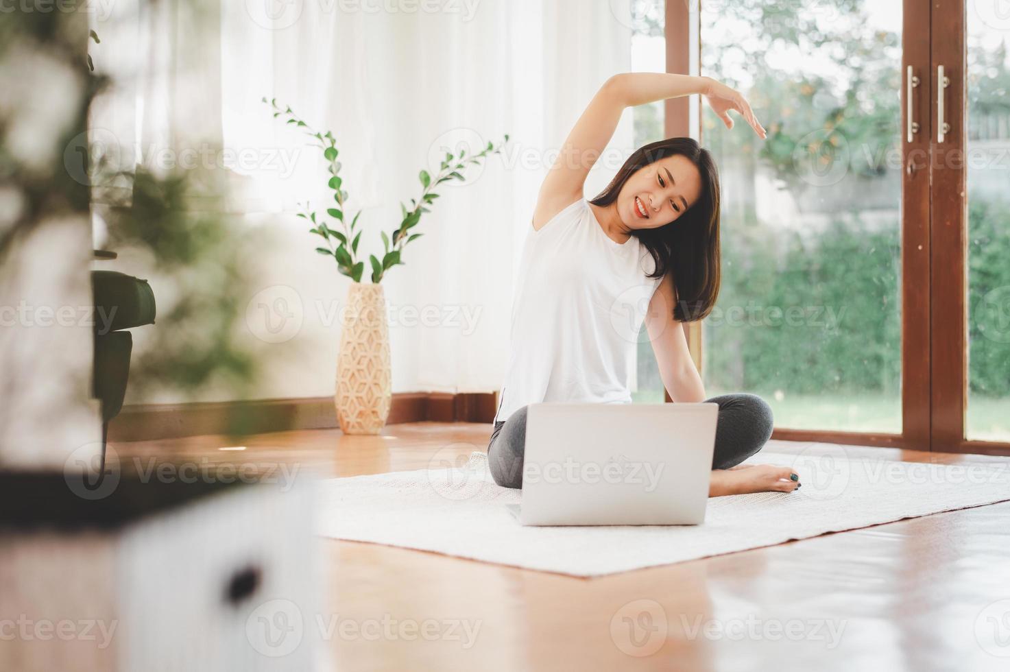 Mulher asiática fitness em casa fazendo alongamento foto