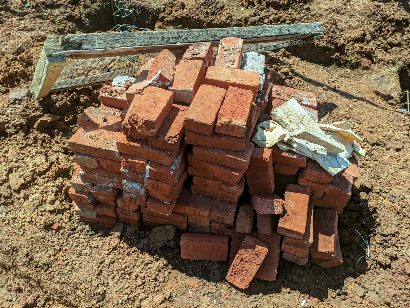 uma pilha do tijolos em a construção local. construção do uma Novo casa. uma pilha do construção materiais, uma pilha do vermelho tijolos para construção é colocar junto. foto