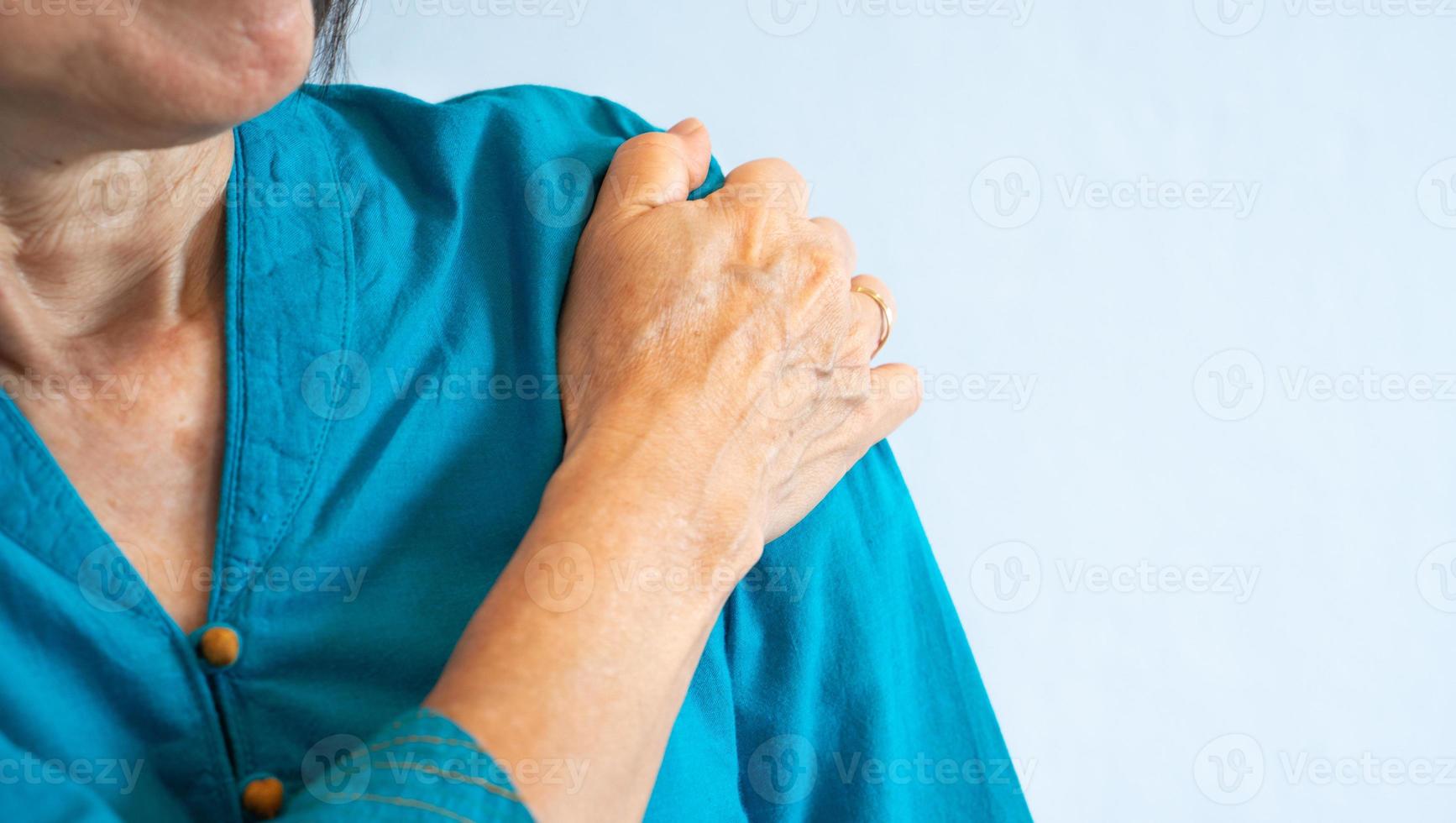 mulher idosa com dor no ombro por causa do ombro congelado foto
