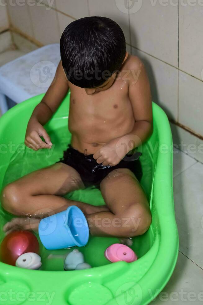 fofa indiano Garoto tendo banho durante a verão período de férias temporada, fofa ásia criança lavando dentro uma banheiro, criança tomando banho estilo de vida conceito foto