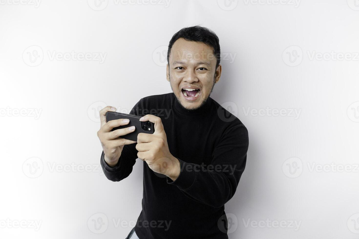 jovem ásia homem dentro casual vestem é jogando jogos com Móvel telefone com uma branco fundo isolado. foto