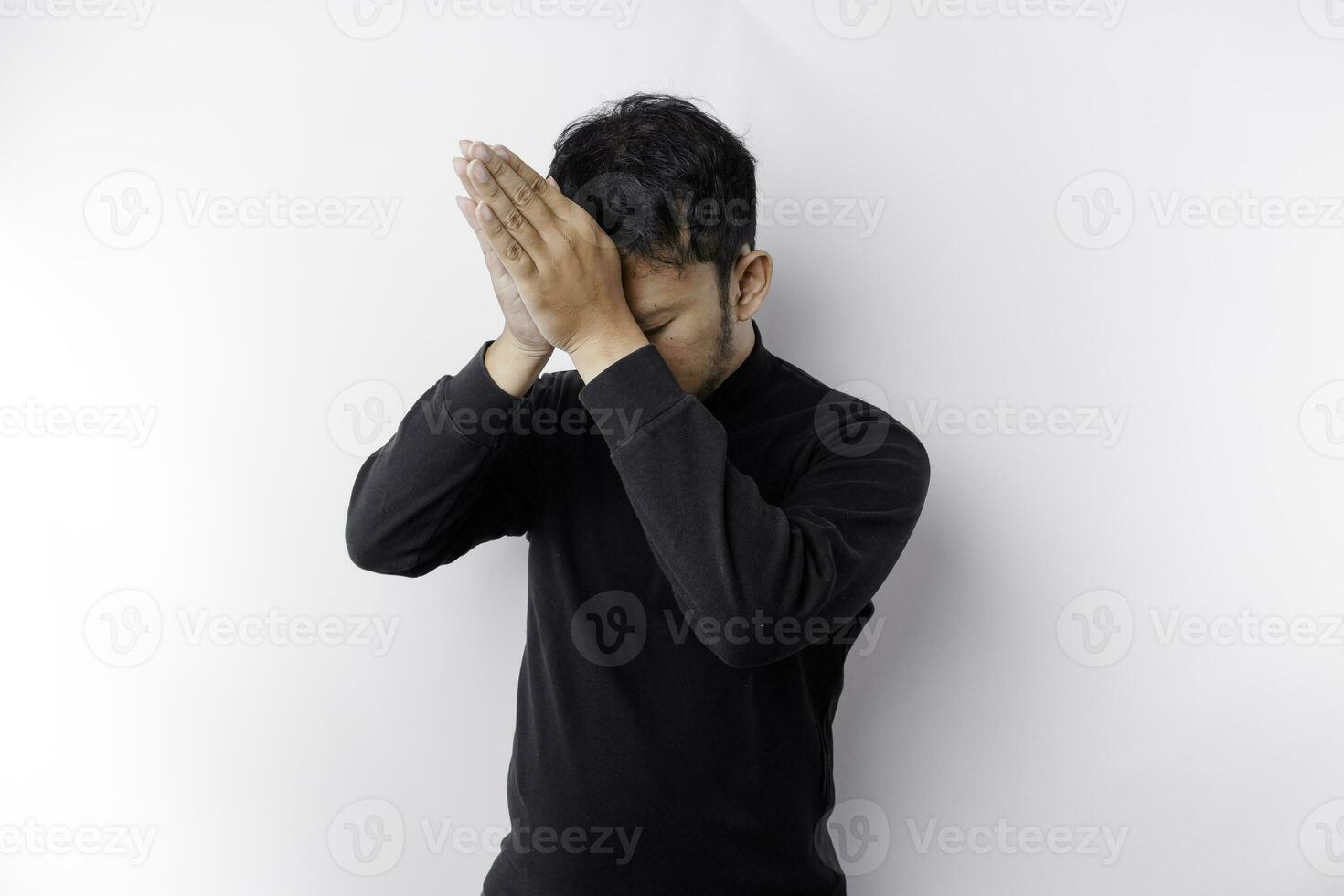 religioso ásia homem vestindo uma Preto camisa Rezar para Deus, isolado de uma branco fundo foto