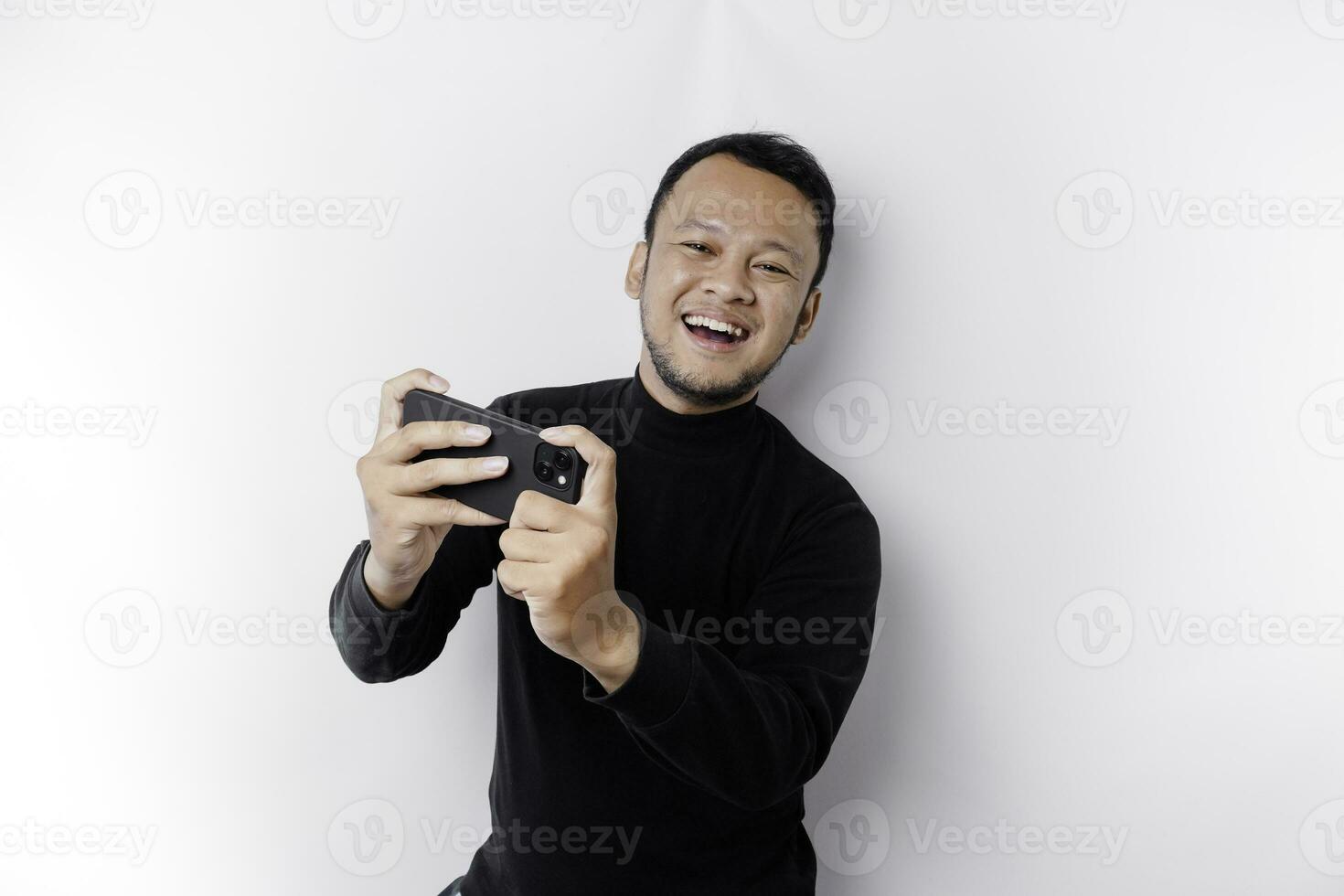 jovem ásia homem dentro casual vestem é jogando jogos com Móvel telefone com uma branco fundo isolado. foto