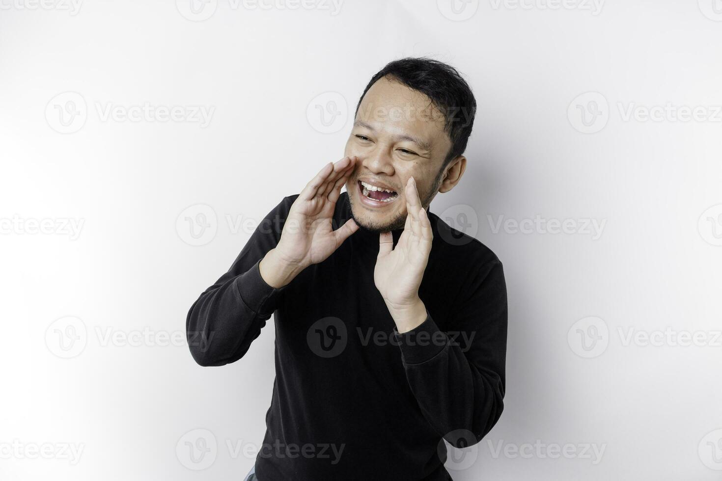 jovem bonito homem vestindo uma Preto camisa gritando e gritando alto com uma mão em dele boca. comunicação conceito. foto