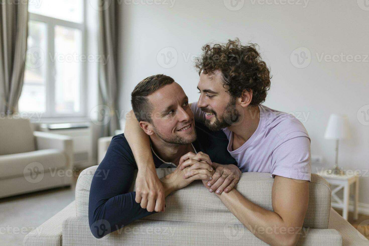 feliz gay casal deitado baixa em a cama às lar, abraçando e flertando. lgbt gay casal amor momentos felicidade conceito foto