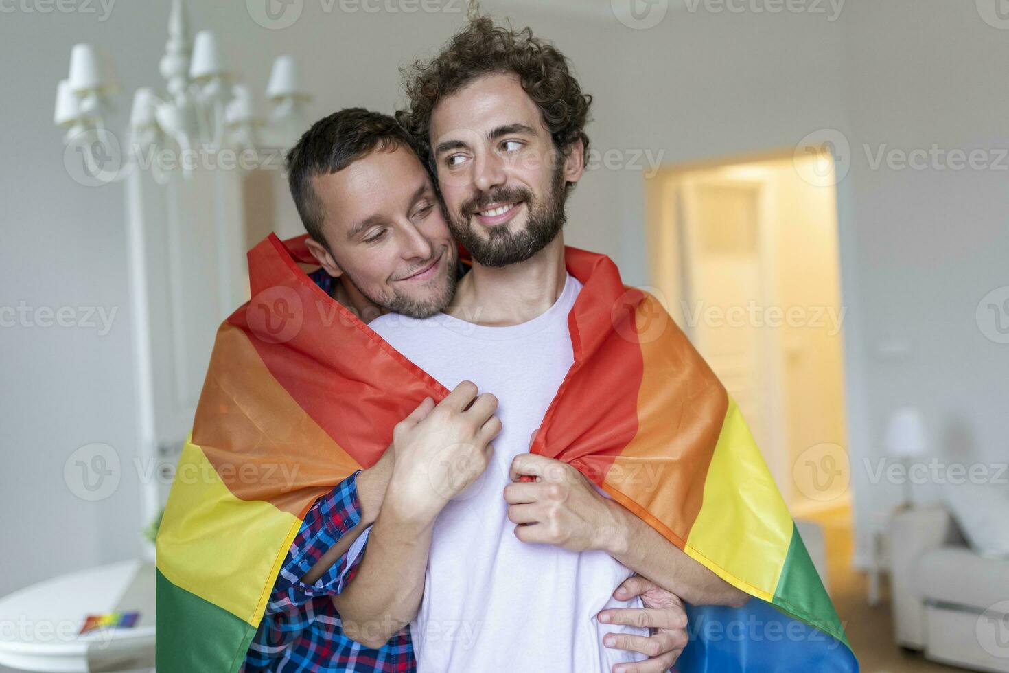 afetuoso masculino gay casal dentro de casa. homem abraçando dele namorado a partir de atrás às lar. gay casal a comemorar orgulho mês foto