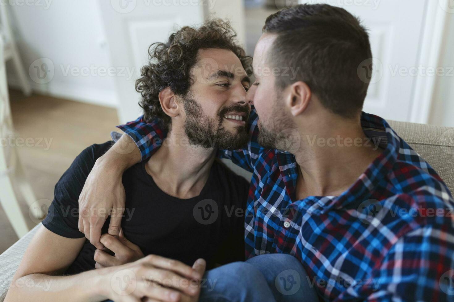 alegre jovem gay casal sentado junto. dois afetuoso masculino amantes sorridente alegremente enquanto abraçando cada outro. jovem gay cupê ser romântico. foto