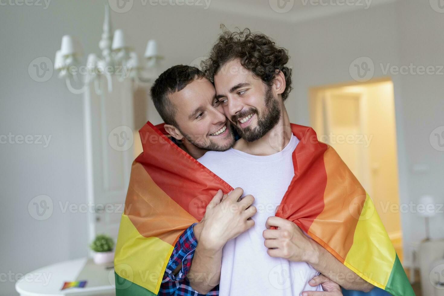 afetuoso masculino gay casal dentro de casa. homem abraçando dele namorado a partir de atrás às lar. gay casal a comemorar orgulho mês foto