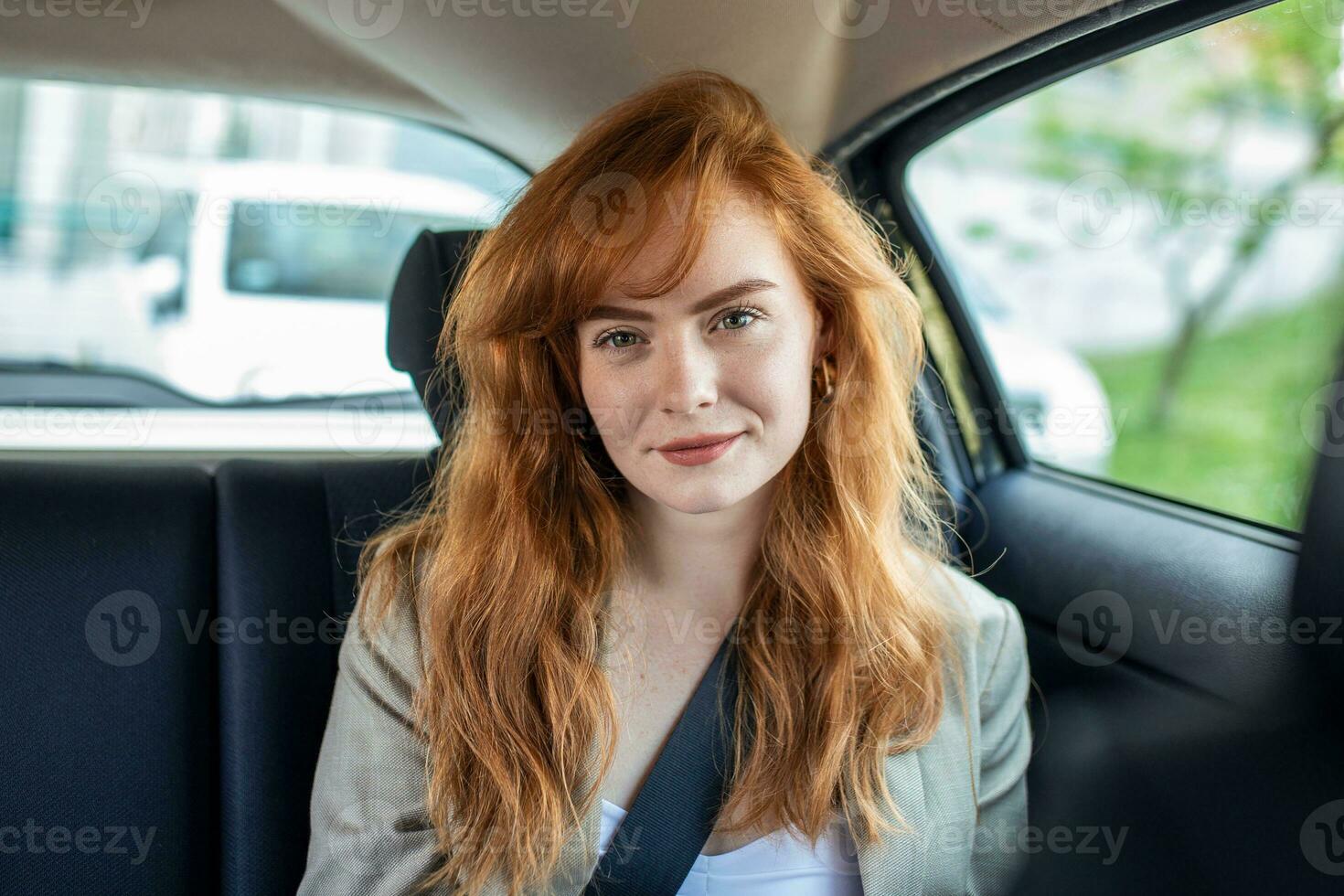 lindo jovem empresária sentado em costas assento do uma carro e olhando às a Câmera. fêmea o negócio executivo viajando de uma táxi. foto