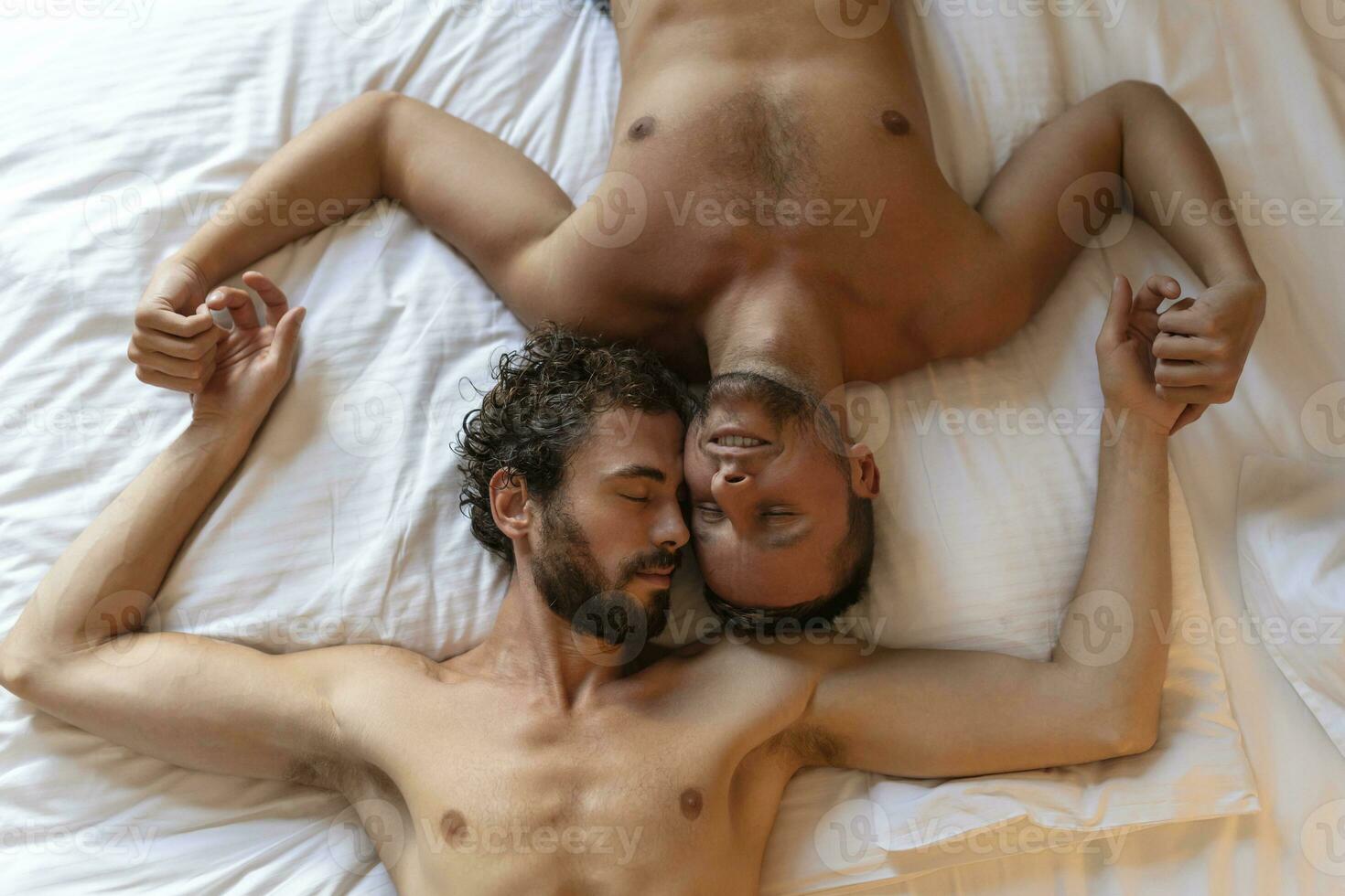 bonito gay casal deitado dentro cama junto. romântico jovem gay casal abraçando cada de outros carinhosamente dentro seus quarto. dois alegre jovem masculino amantes vínculo com carinho às lar. foto