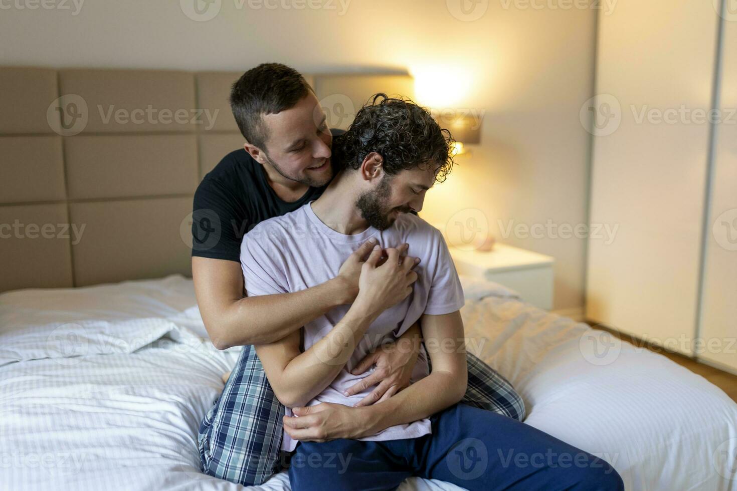 gay casal abraçando cada de outros com seus olhos fechado. dois jovem masculino amantes tocante seus rostos juntos enquanto dentro cama dentro a manhã. afetuoso jovem gay casal vínculo às lar. foto
