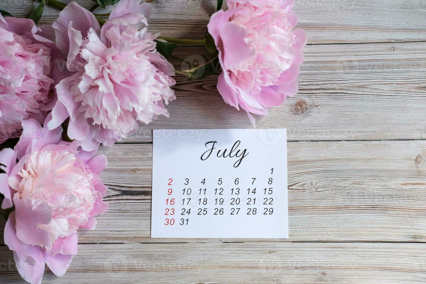 Julho calendário e uma ramalhete do peônias foto