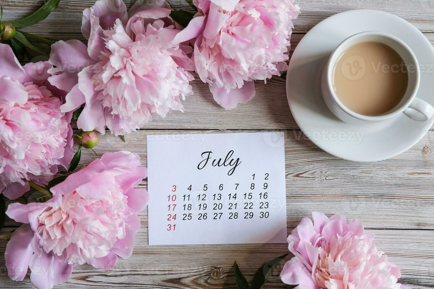 Julho calendário, peônias e uma copo do café em a mesa. mulheres Área de Trabalho foto