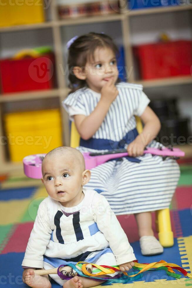 dois pequeno meninas jogando instrumentos dentro de casa foto