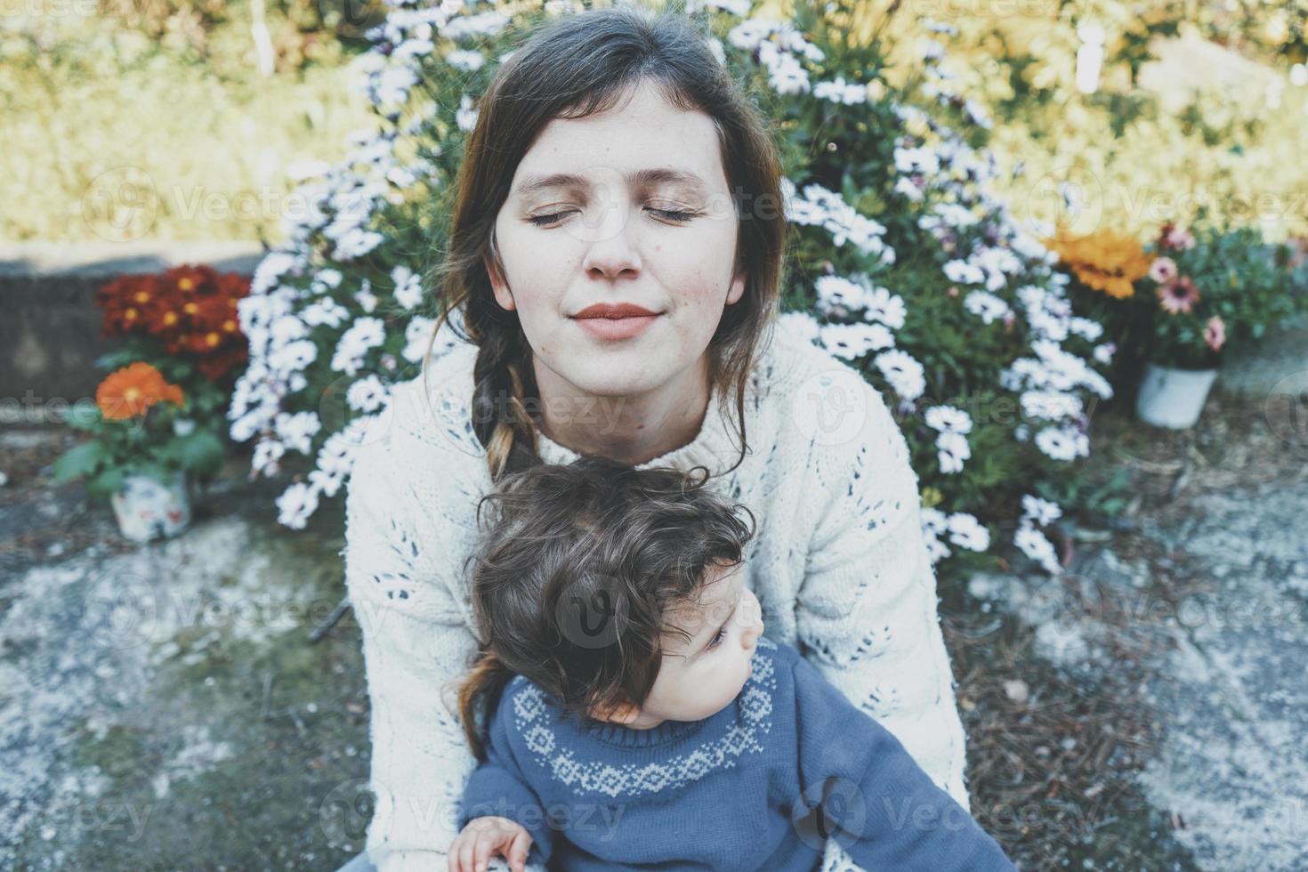 jovem mãe abraçando seu bebê e curtindo um dia de primavera no jardim foto