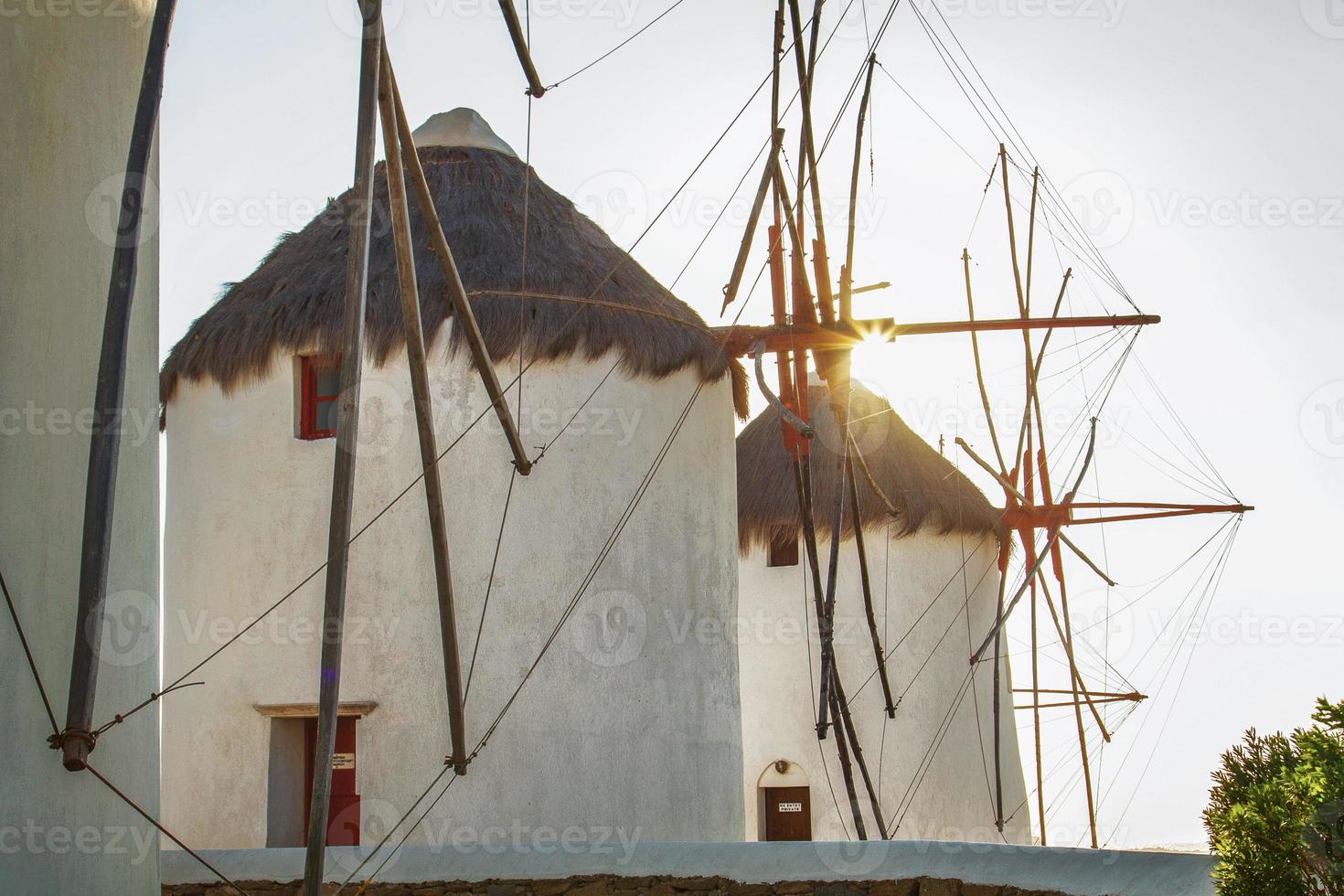 moinhos de vento em mykonos, grécia, retroiluminados pelo sol foto