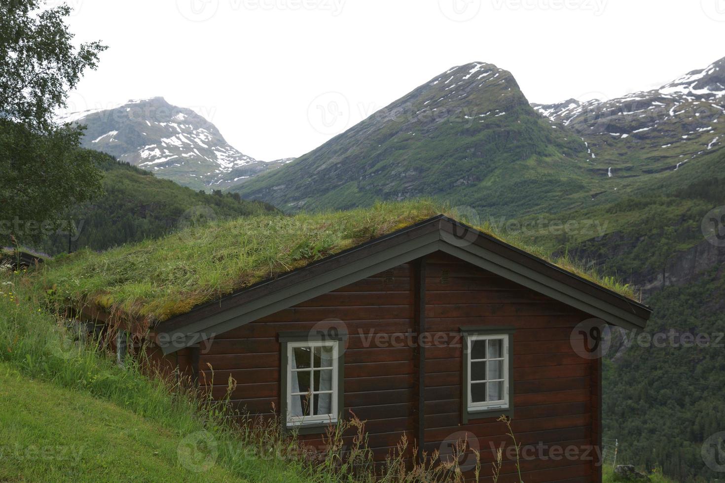 típica casa de madeira antiga com telhado de grama nos fiordes de geiranger, na Noruega foto