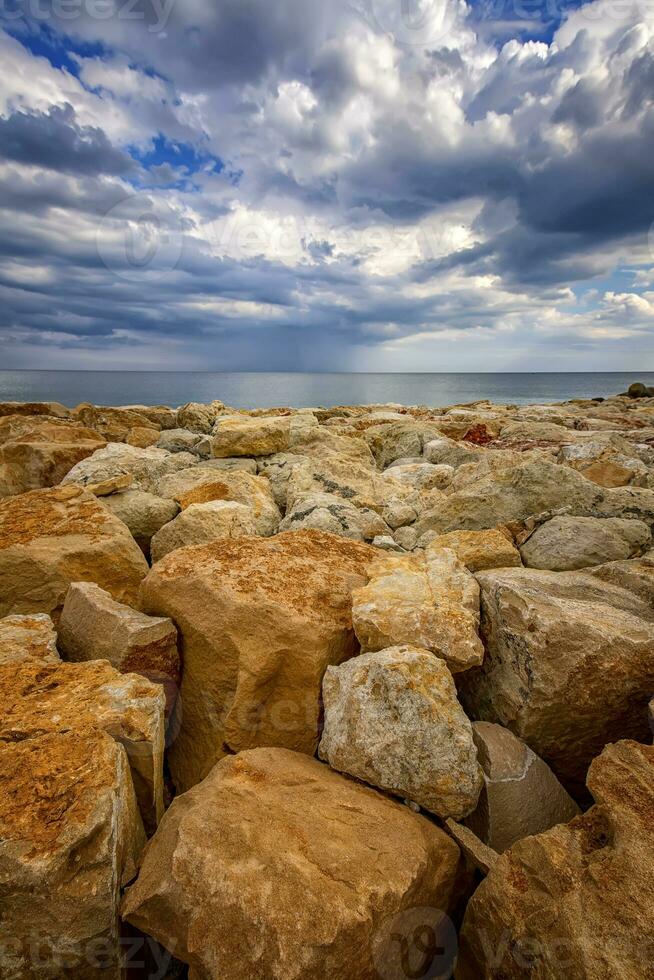 lindo pedra costa marinha com colorida pedras. vertical Visão foto