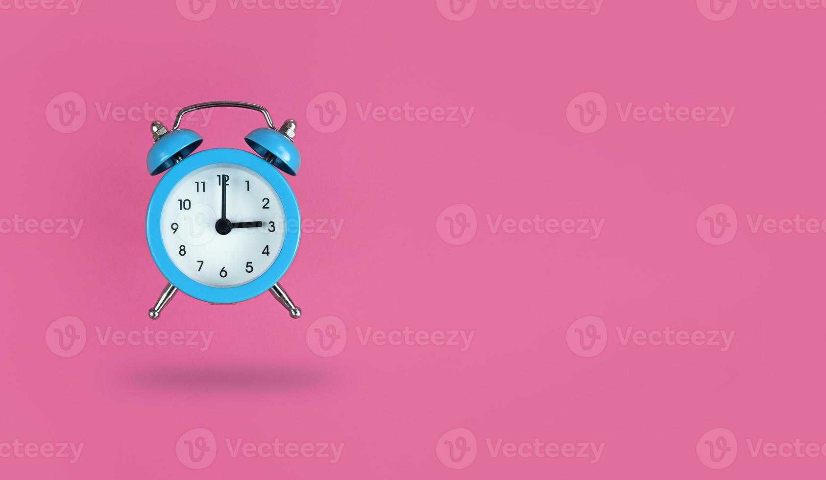 levitando despertador azul em fundo rosa com espaço de cópia foto
