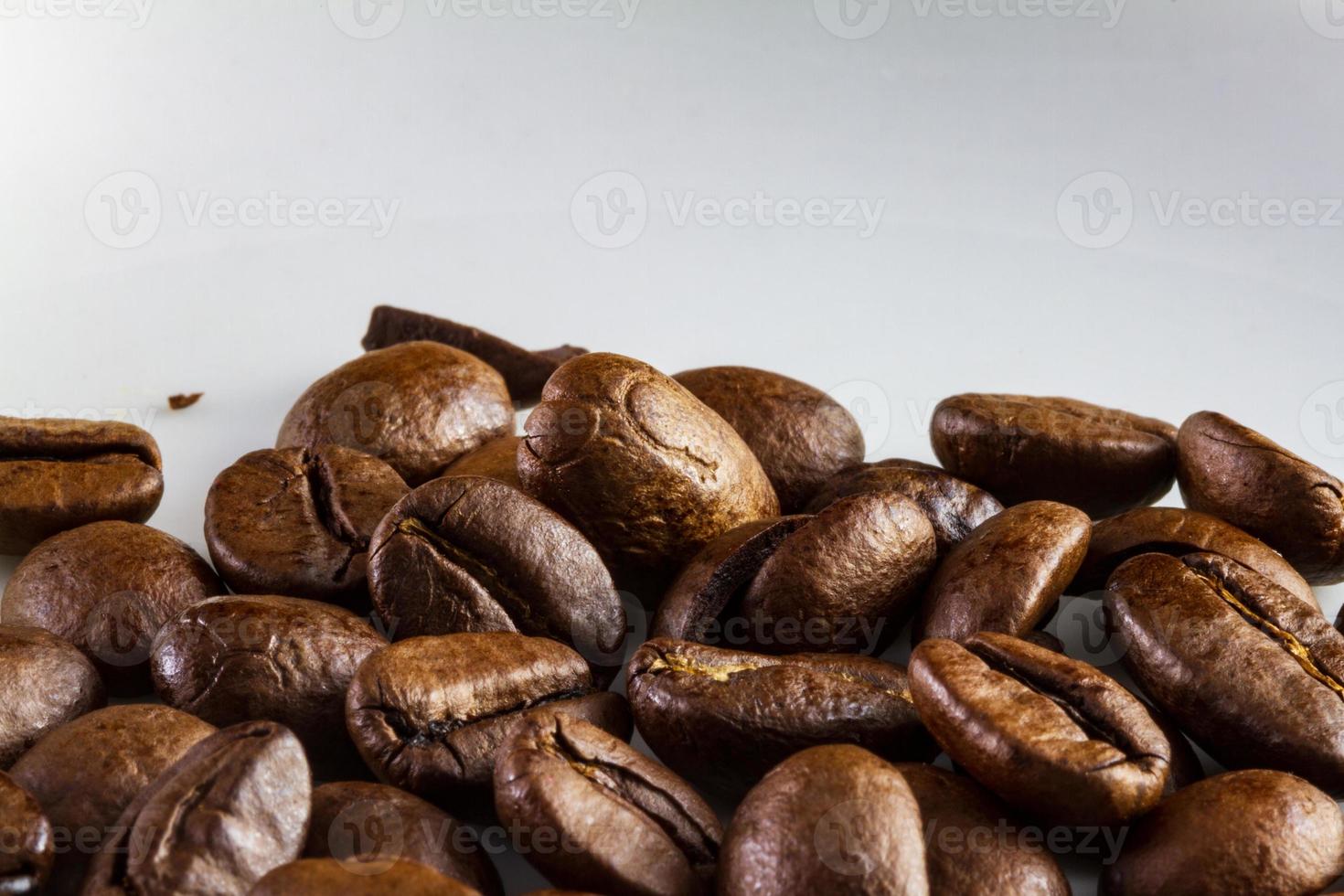 macro de grãos de café em uma xícara de café branco foto