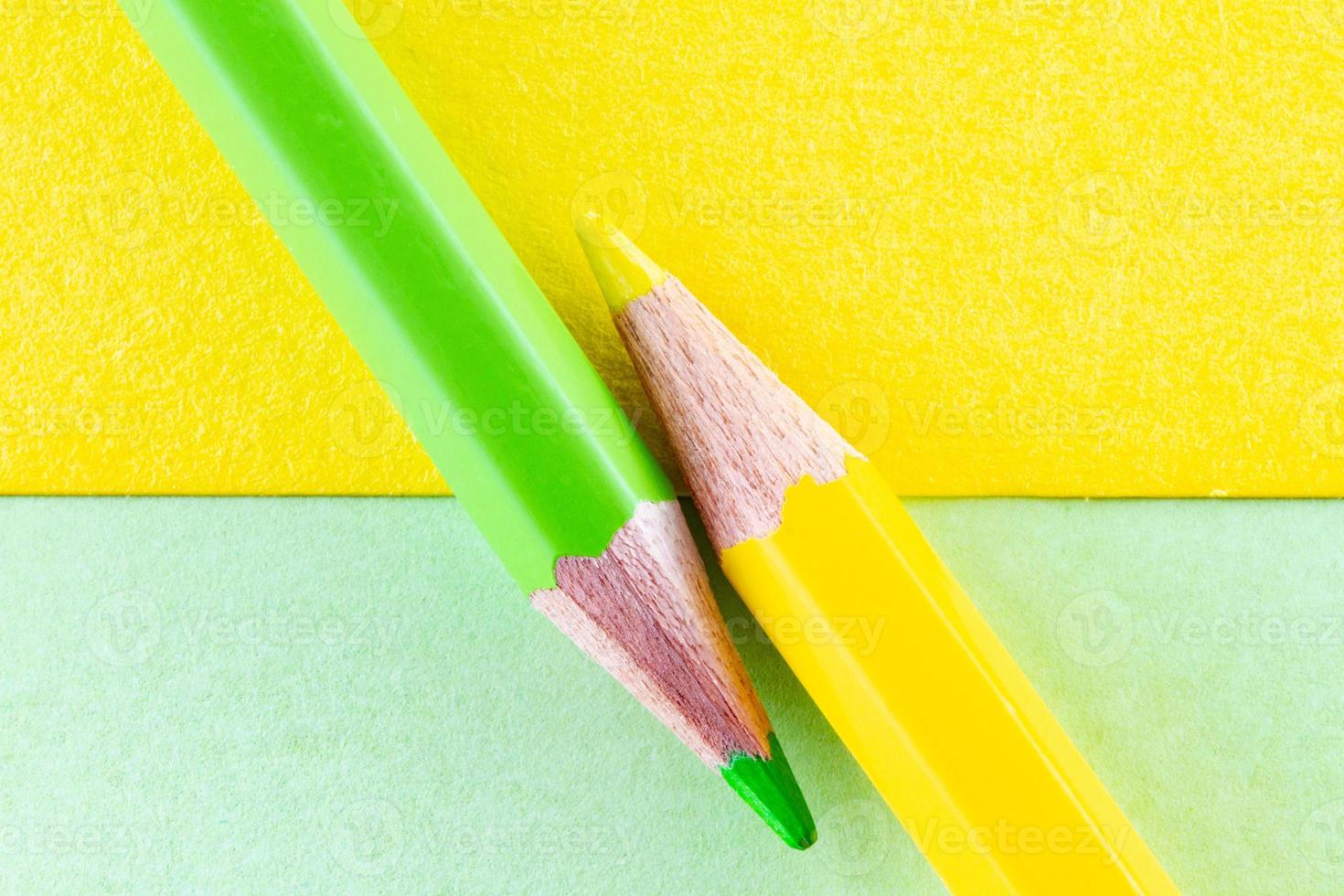 lápis de cor em papéis de cor amarela e verde dispostos diagonalmente foto