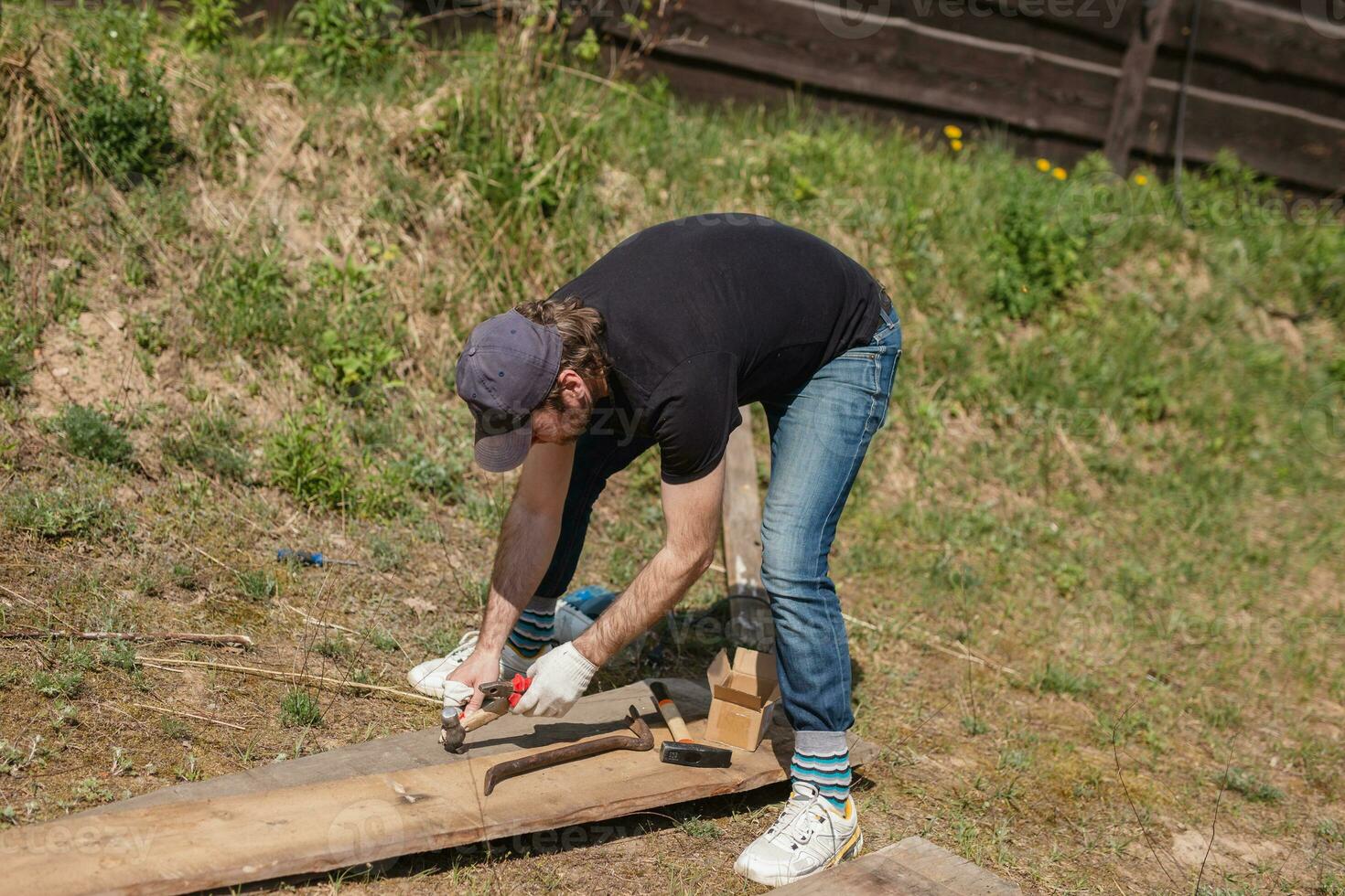 homem constrói Seções do cerca por aí dele Jardim Fora do pranchas - verão casa tarefas dentro a quintal foto