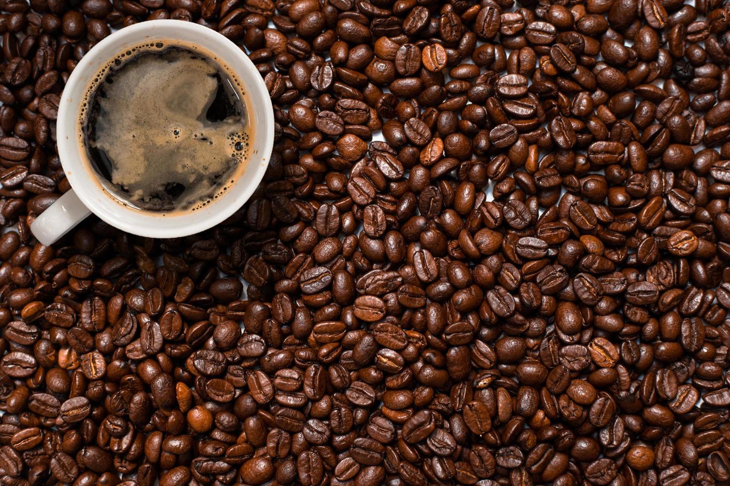 vista superior de uma xícara de café em uma pilha de grãos de café foto