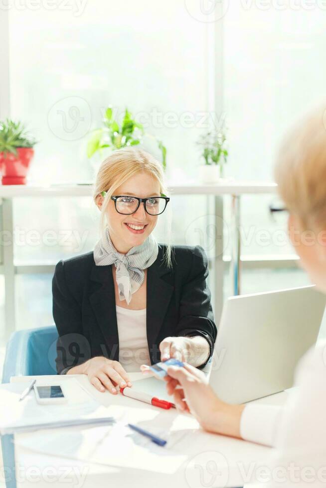 lindo fêmea trabalhador emissão crédito cartão para uma cliente foto
