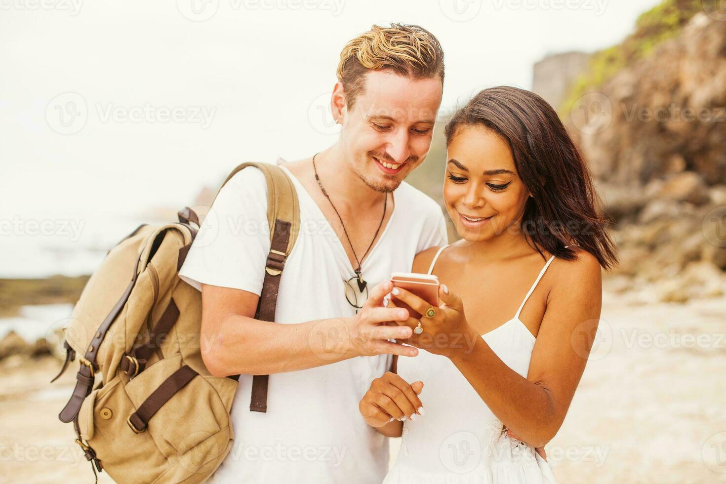 mestiço casal Viajantes olhando às a aplicativo em Móvel telefone foto