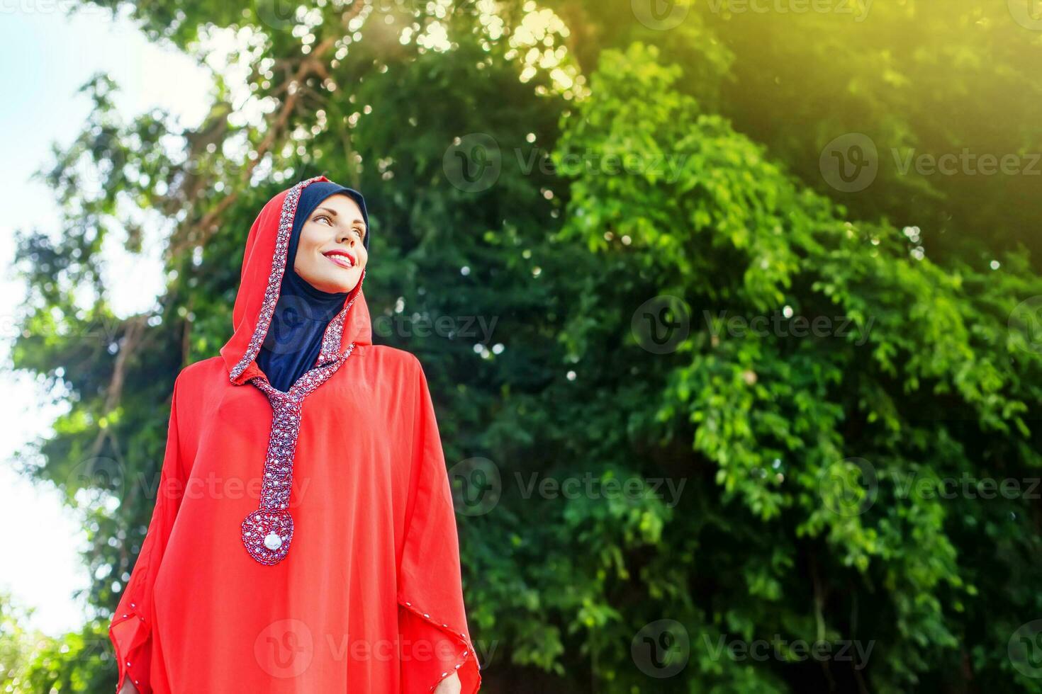 lindo muçulmano caucasiano mulher vestindo vermelho vestir e hijab dentro a parque foto