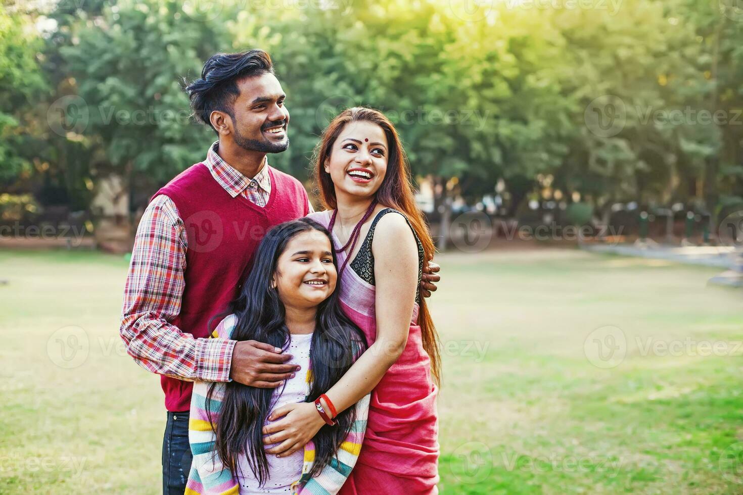 lindo indiano família com 10 anos de idade filha em pé juntos dentro uma parque foto