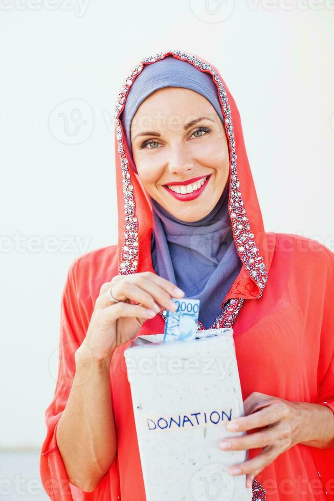 muçulmano caucasiano mulher dando esmolas foto