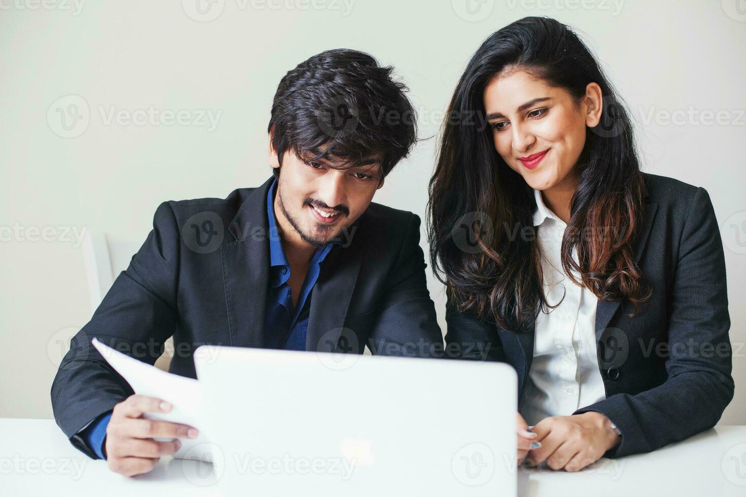 dois indiano colegas trabalhando Como uma equipe em uma computador portátil dentro escritório foto
