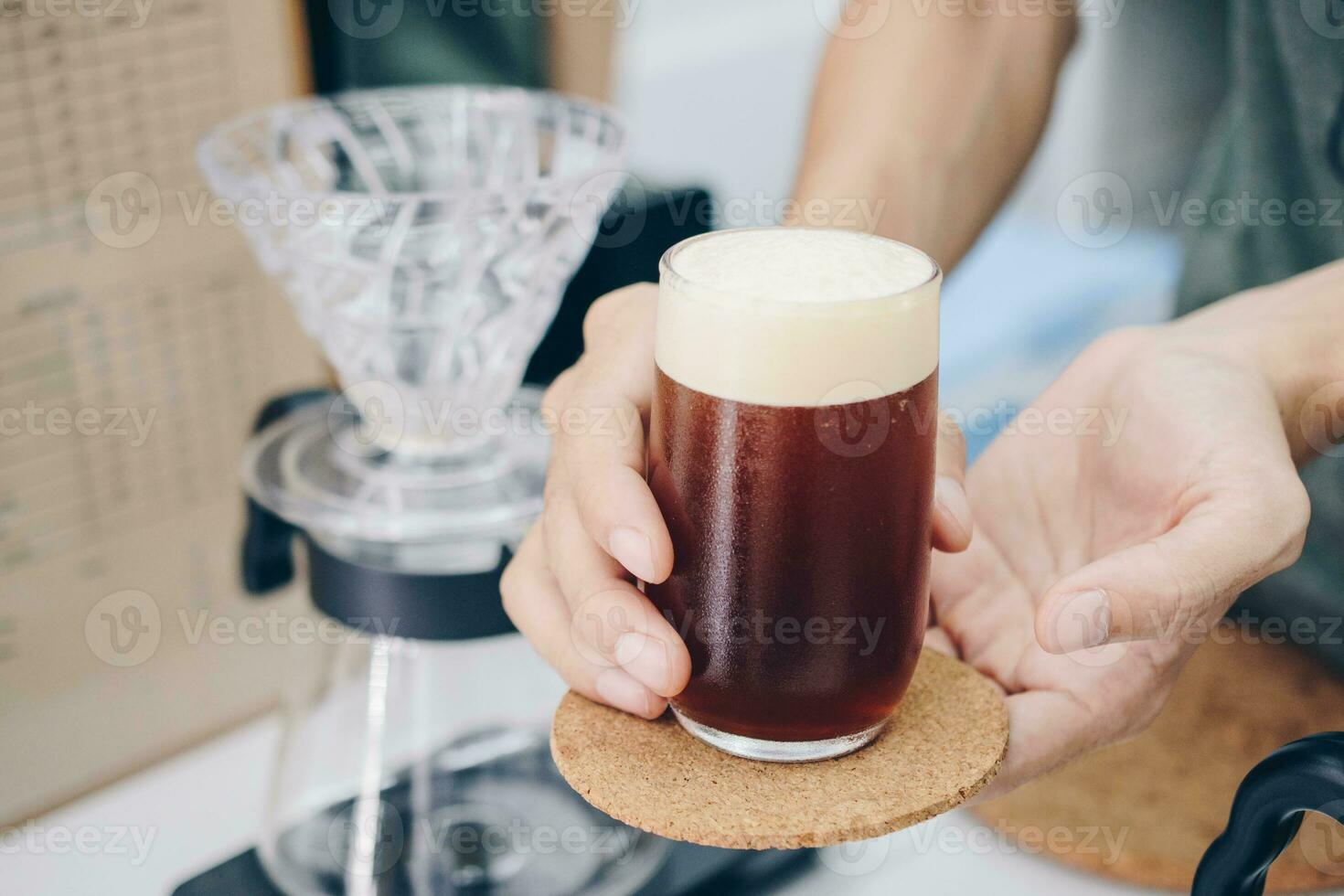 barista segurando e servindo uma bebendo vidro do frio preparar mergulho café. foto