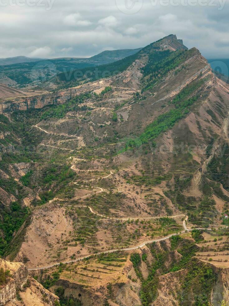 vertical Visão do uma montanha vale com uma serpentina estrada. perigoso limitar sujeira montanha estrada através a colinas para uma grande altitude Vila. foto