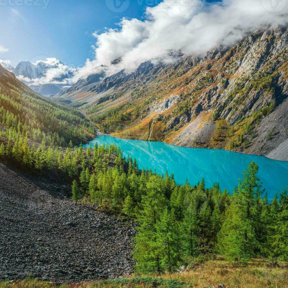 colorida outono panorama com Claro montanha lago dentro floresta entre abeto árvores dentro luz do sol. brilhante cenário com lindo turquesa lago contra a fundo do Alto montanhas. mais baixo shavlin lago. foto