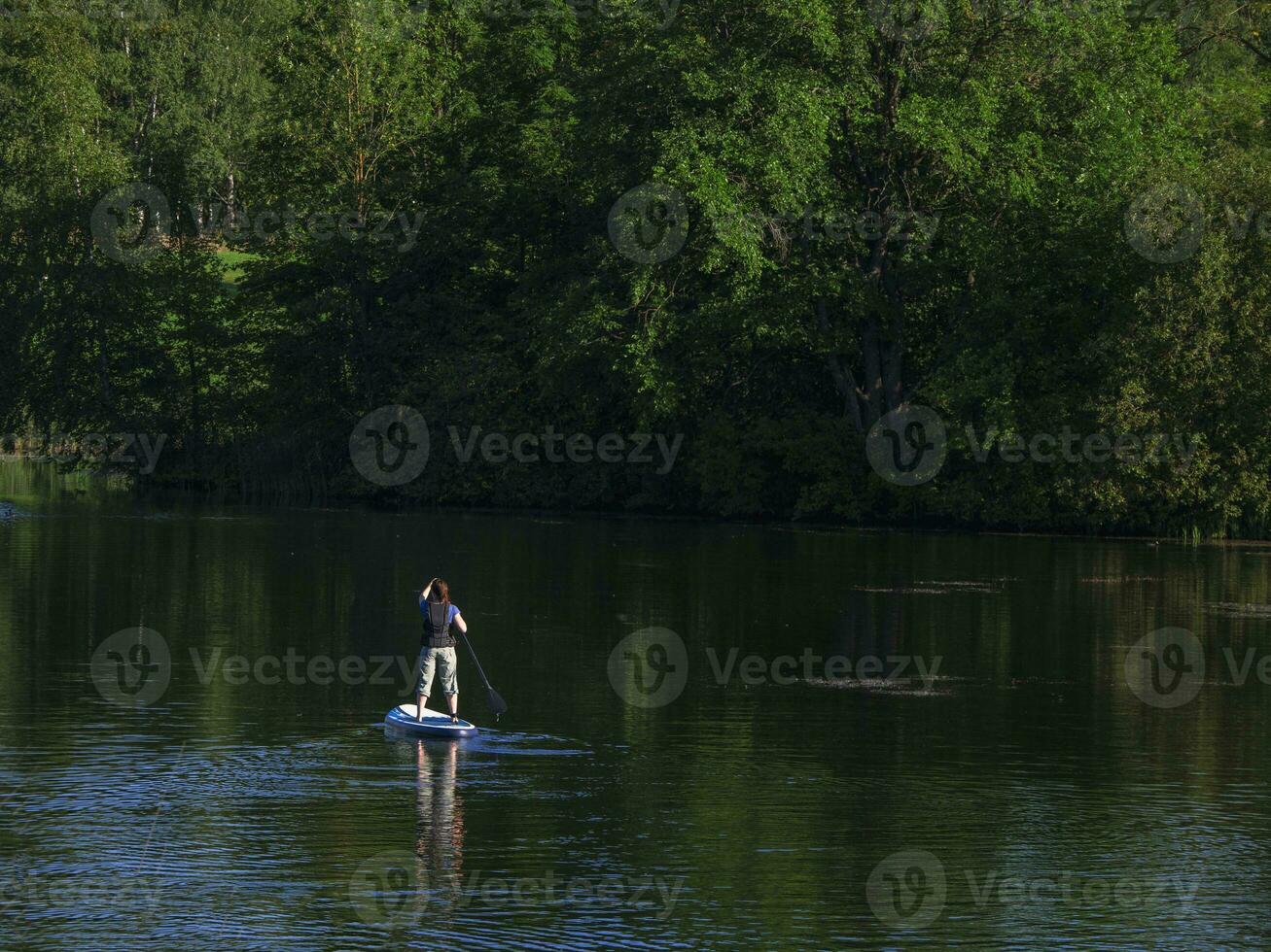 mulher Navegando em lindo calma verde lagoa. verão feriados período de férias viagem. sup ficar de pé acima remo borda foto