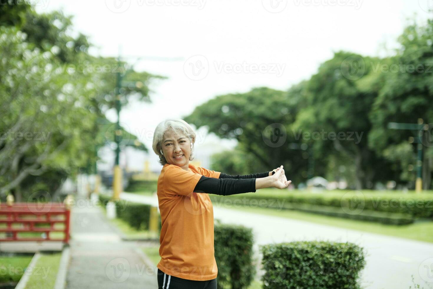 Atlético Senior mulher alongamento braços dentro parque. foto