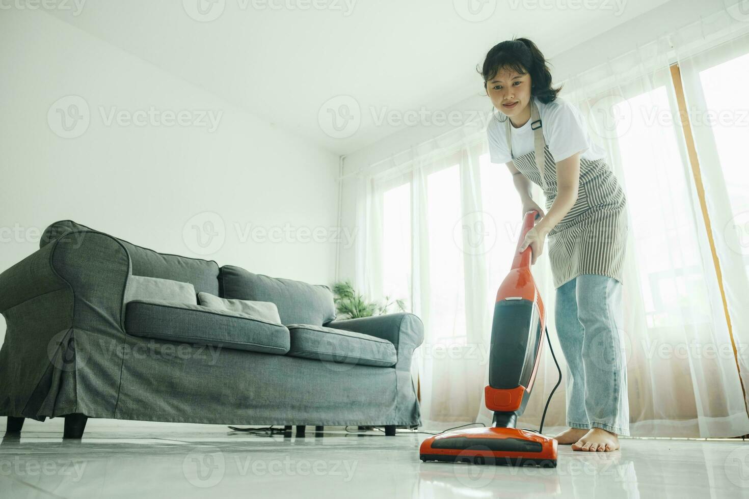 jovem mulher limpeza casa com vácuo limpador. foto