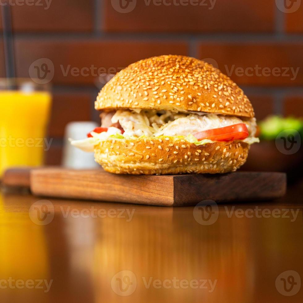 batata frita caesar hambúrguer no prato de madeira com suco de laranja foto