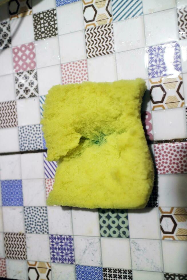 uma quebrado amarelo espuma usava para lavando pratos é colocada em a telha foto