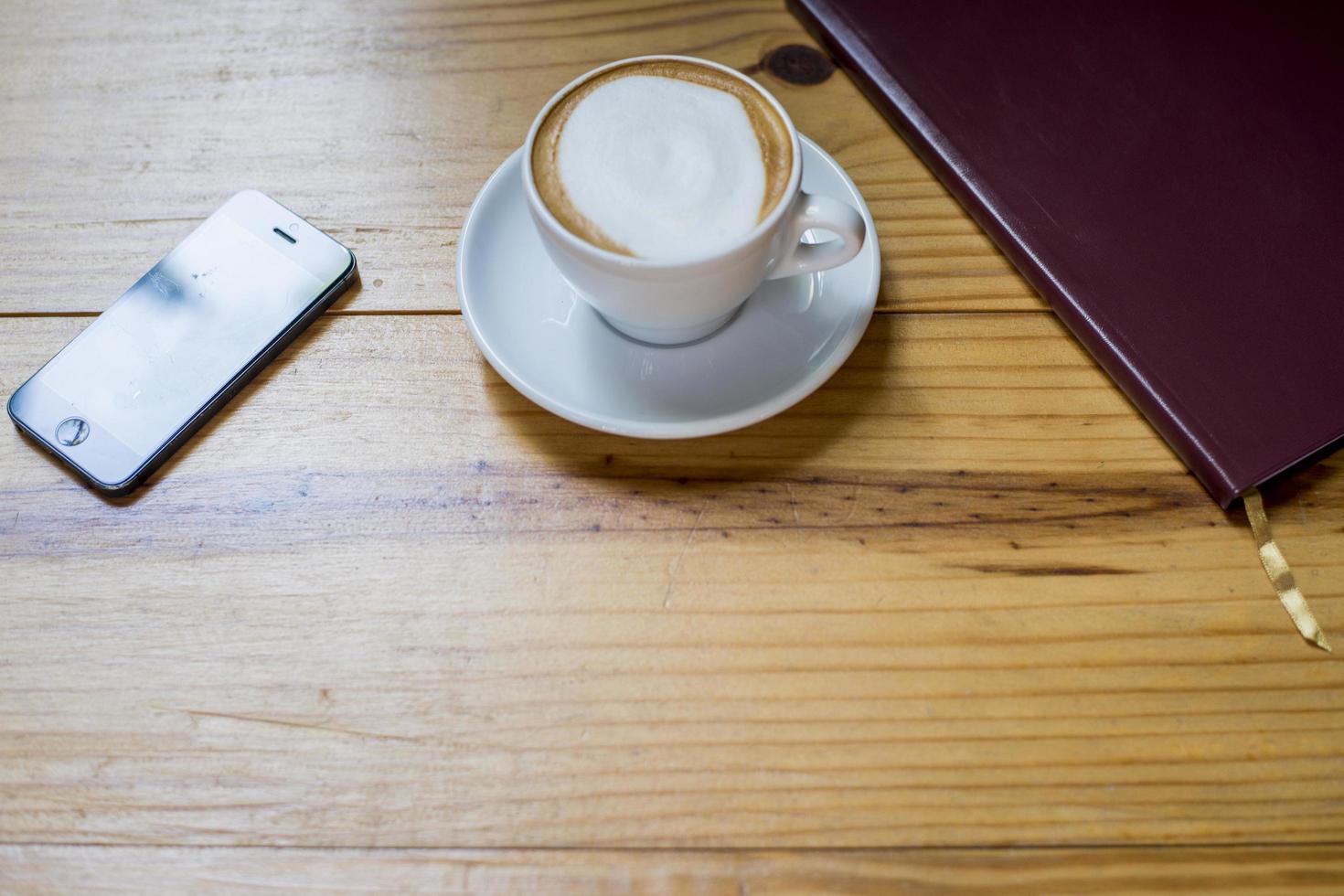 caderno com xícara de café na mesa de madeira foto