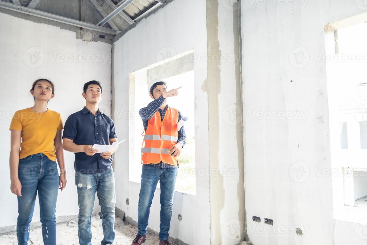 jovem casal asiático verificando a casa com o engenheiro chefe durante a inspeção residencial foto
