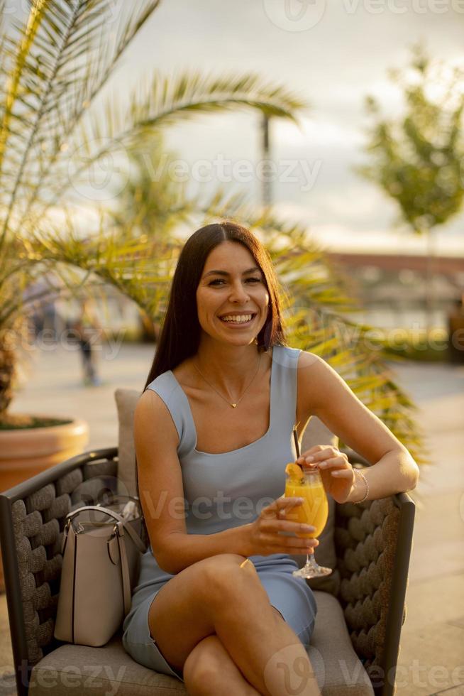 jovem bebendo suco de laranja no café da rua foto